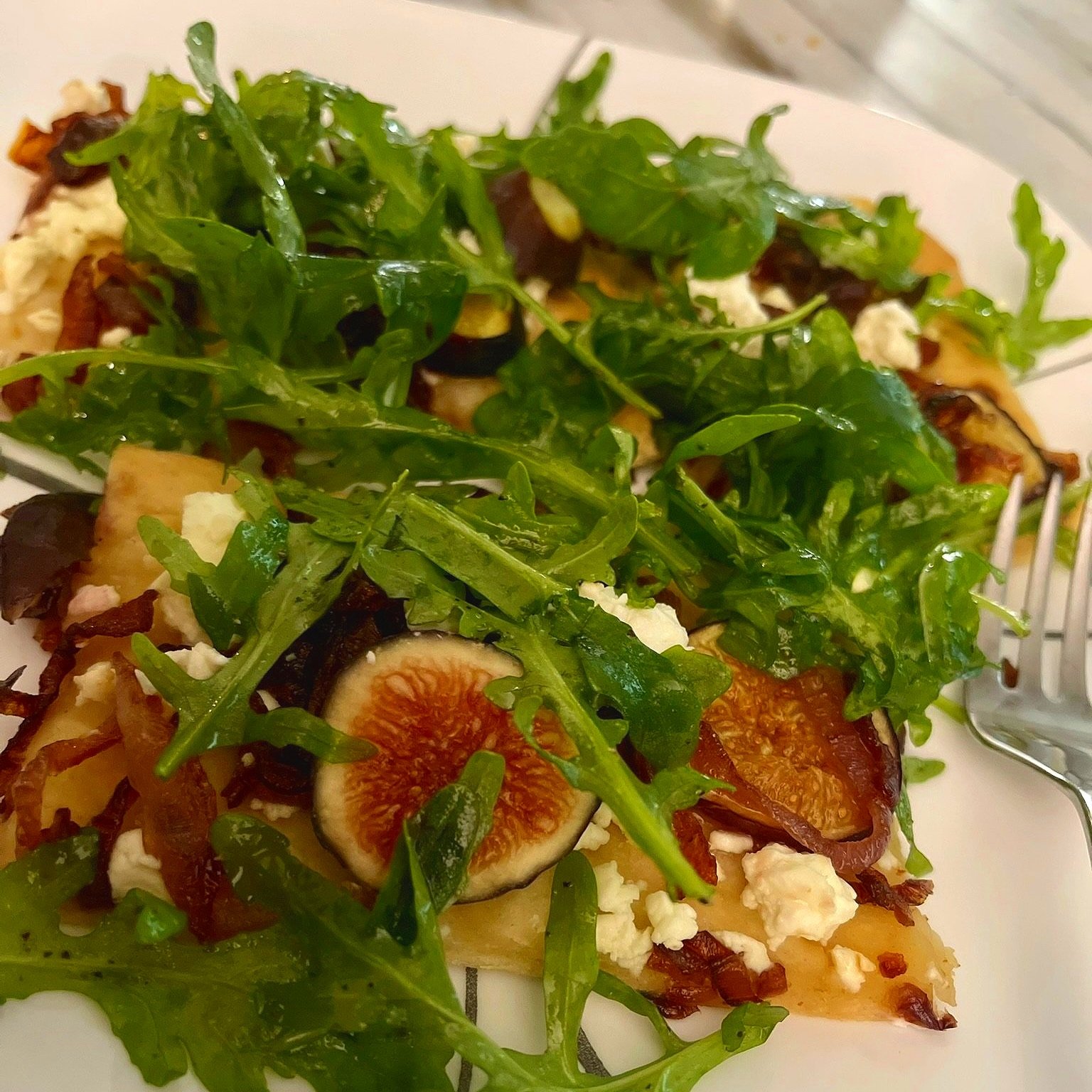Close-up of the fig, feta, and arugula flatbread pizza on a wooden board