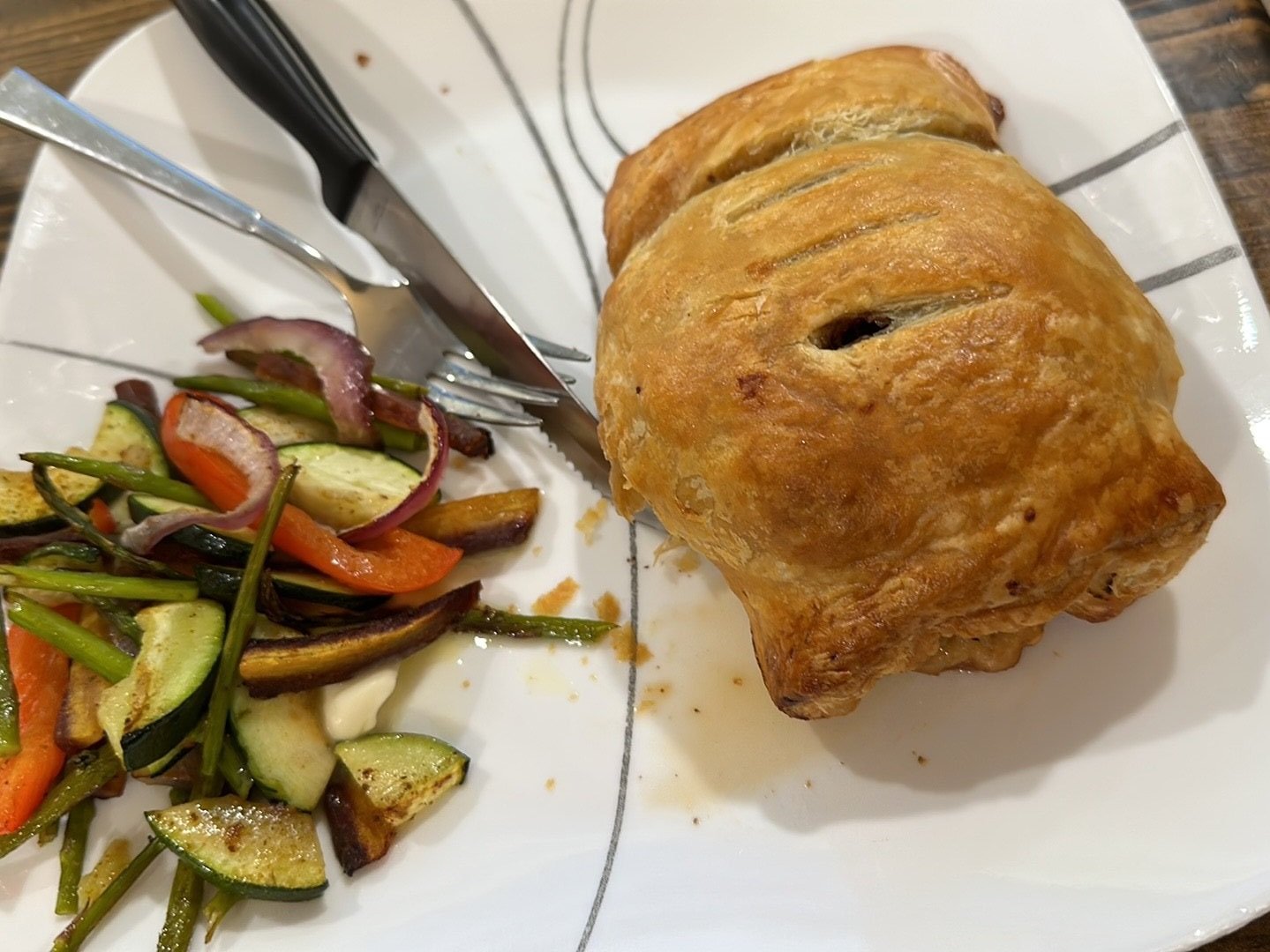 A hand-crimped meat pie fresh from the oven, its golden pastry cut open to reveal the meaty filling inside