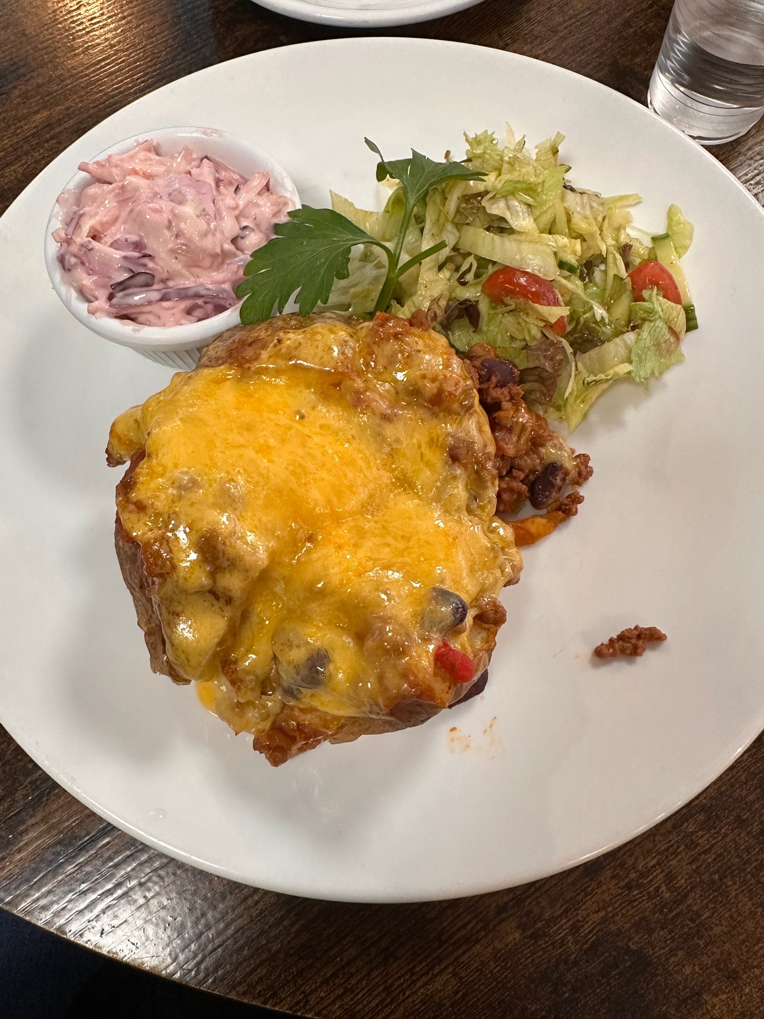 A split baked potato topped with chili con carne, cheese, and sour cream