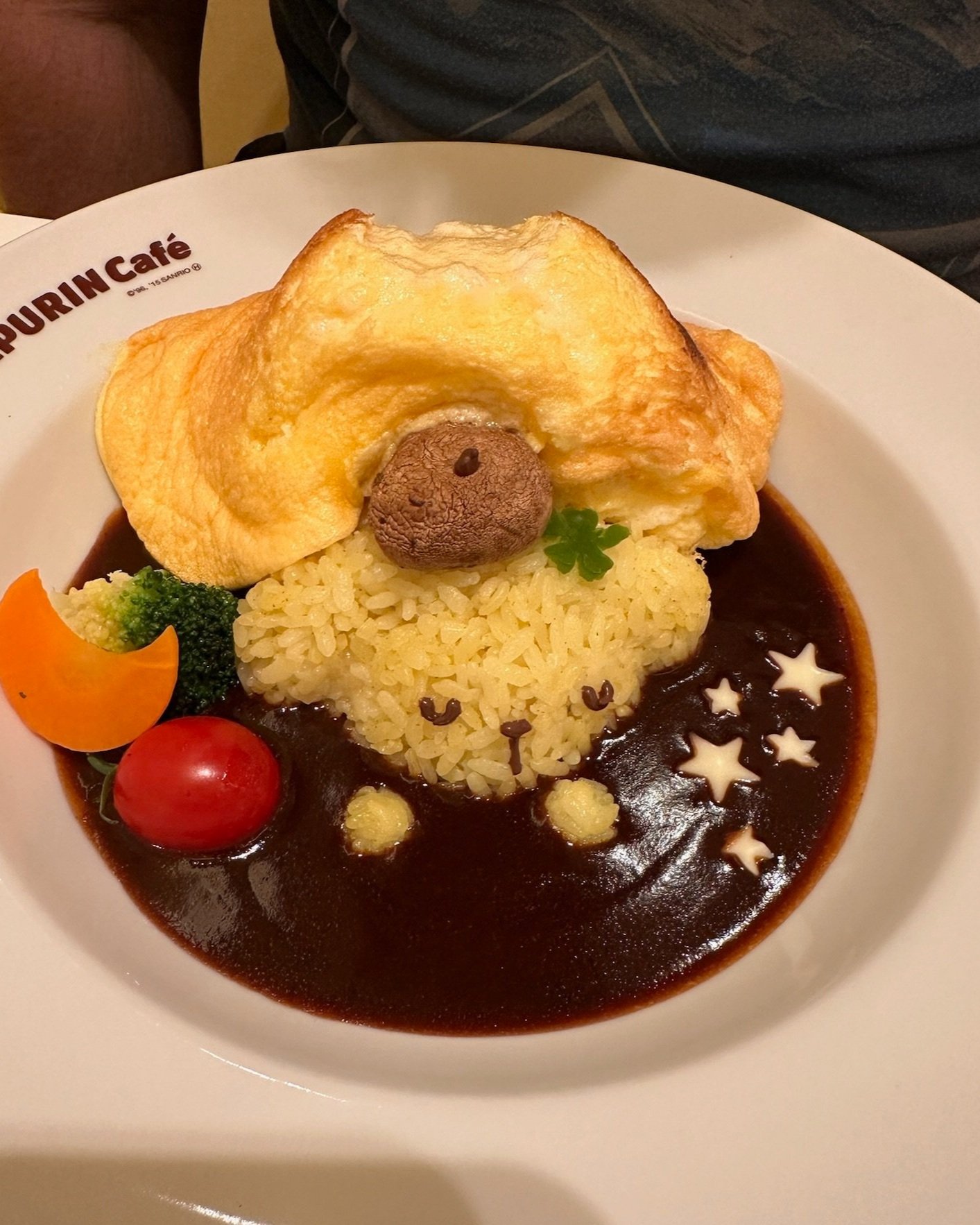 A heart-shaped plate of omurice at Pompompurin Cafe, fluffy omelette draped over ketchup fried rice