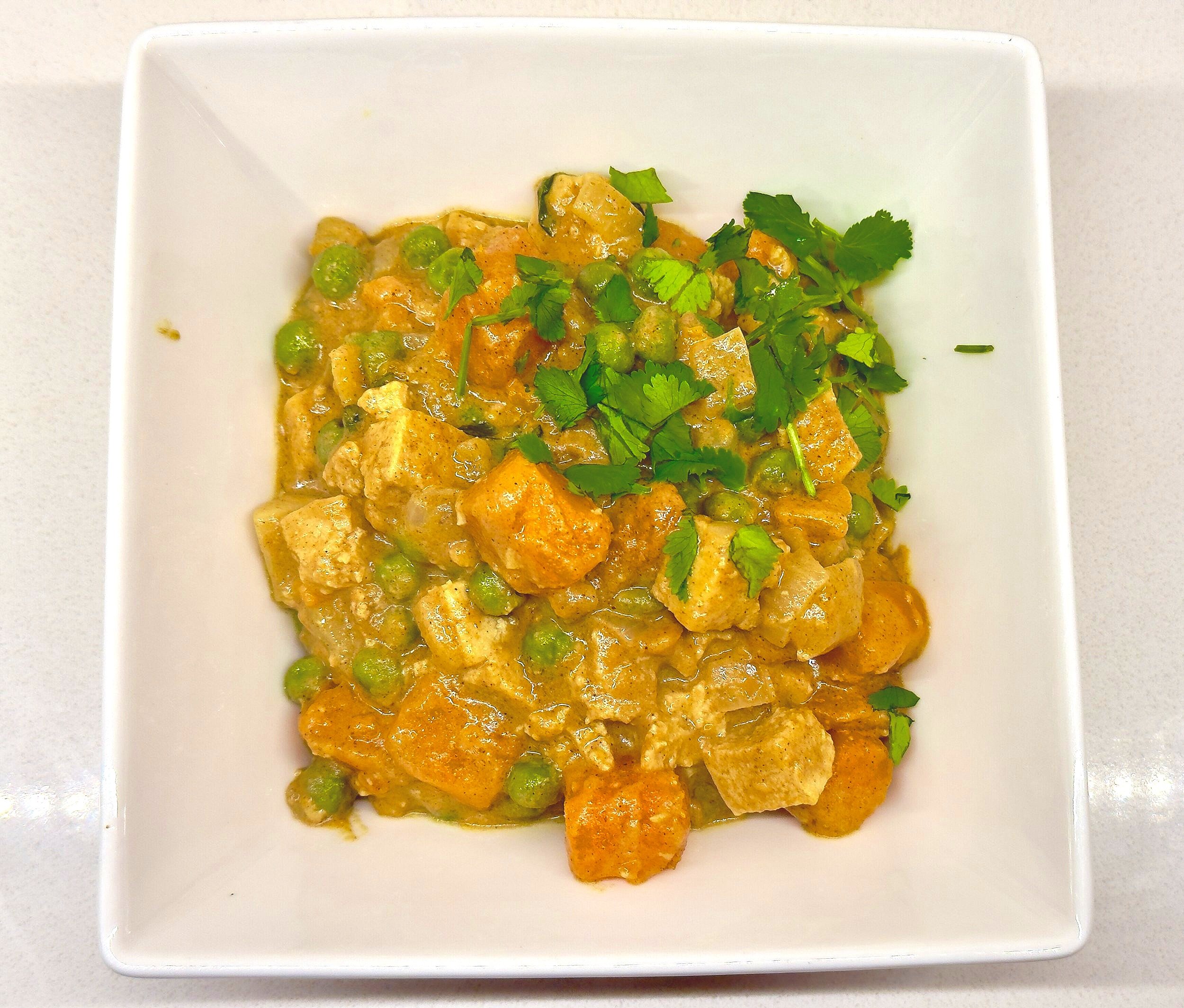 Close-up of coconut curry with tofu simmering in a pan